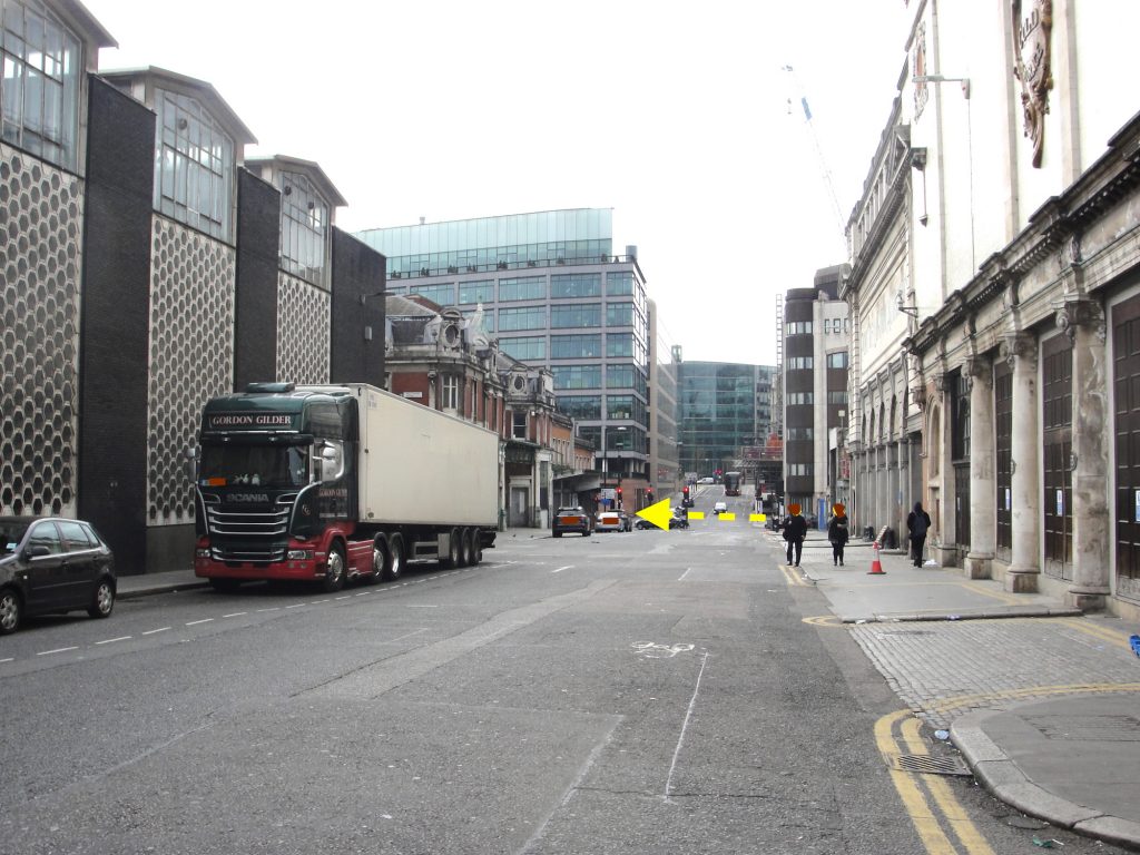 On Charterhouse Street, London, looking west. If you look carefully you can see that the roads runs downhill and then rises again after the yellow arrow. A yellow arrow shows the former line of the River Fleet running down into Farringdon Street.